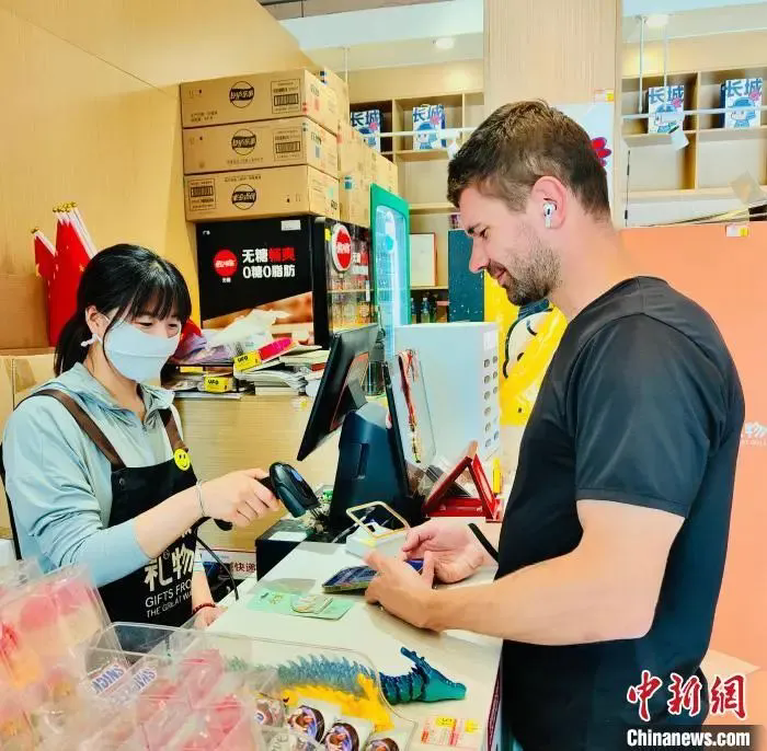 圖為外籍游客在北京八達(dá)嶺長城景區(qū)商店內(nèi)體驗(yàn)電子支付。