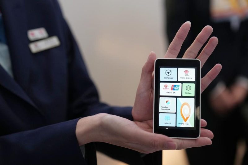 在北京首都國(guó)際機(jī)場(chǎng)T3航站樓的“北京服務(wù)”機(jī)場(chǎng)服務(wù)點(diǎn)，一位工作人員在展示“兩卡融合”終端。
