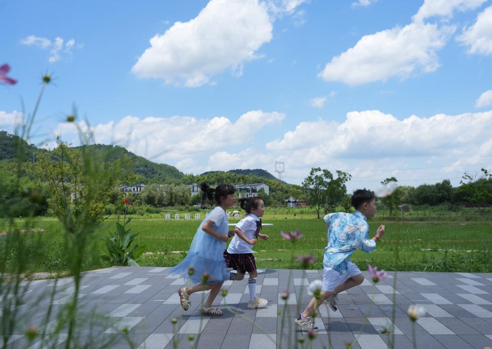兒童在余姚市梁弄鎮(zhèn)的田野間奔跑（7月3日攝）。