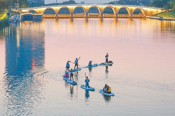 北運河上玩槳板的年輕人。